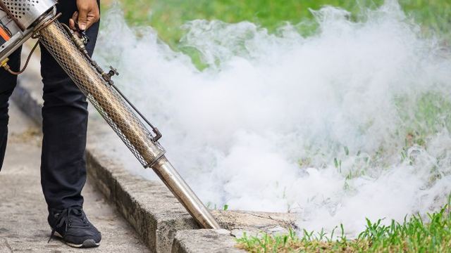 Técnico con máquina de nebulización generando humo insecticida junto a una zona ajardinada en el blog de Control de Plagas León