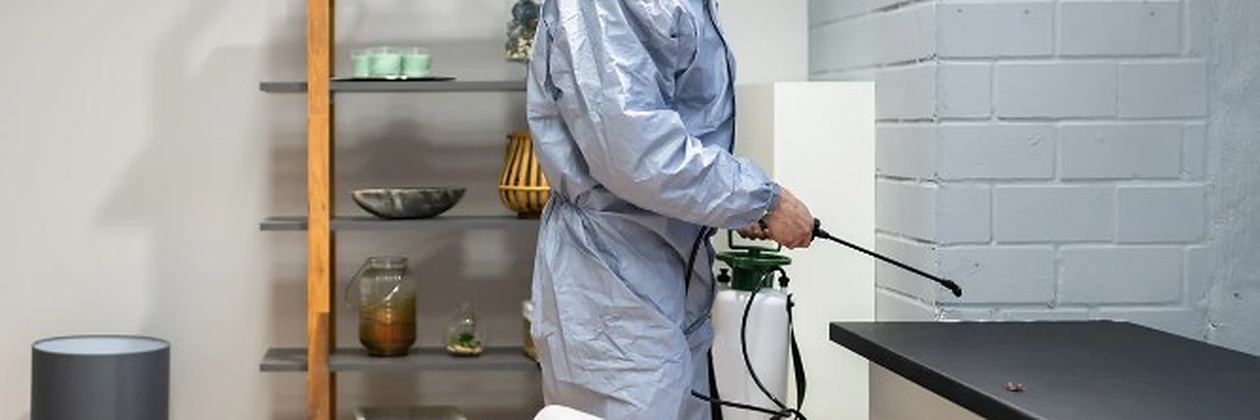 Técnico con equipo de protección aplicando tratamiento junto a una encimera de cocina en un servicio de control de plagas en Onzonilla Técnico con equipo de protección aplicando tratamiento junto a una encimera de cocina en un servicio de control de plagas en Onzonilla